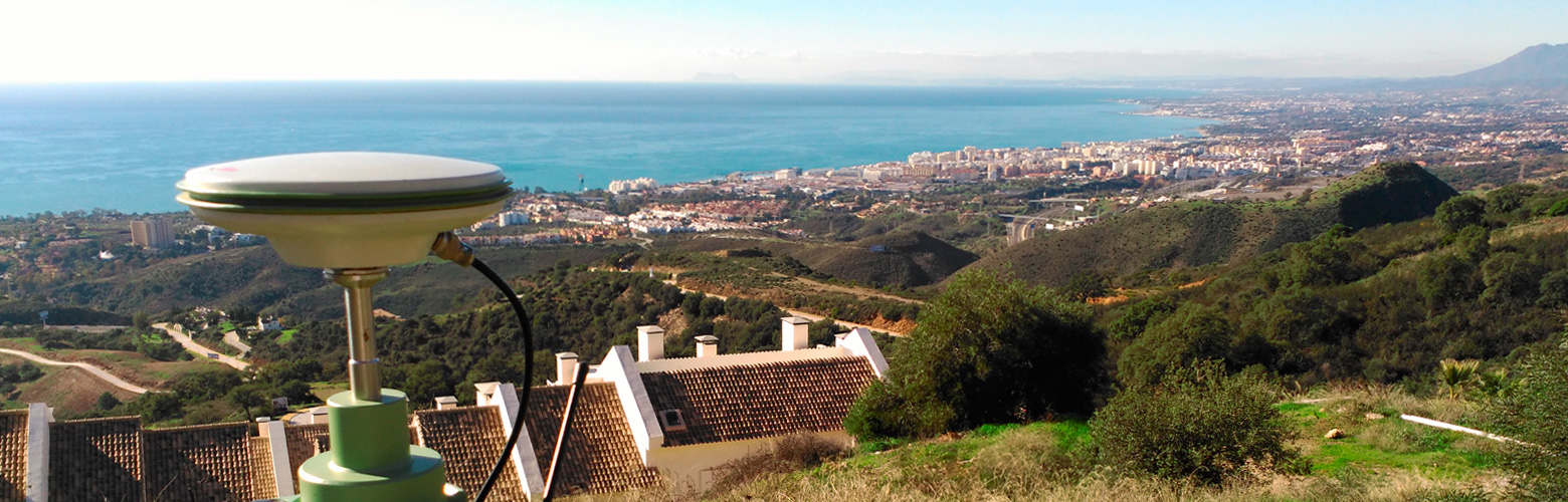 Equipo GPS de topografía sobre un mirador con vista al mar Mediterráneo y la costa de Málaga.